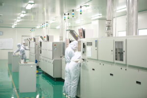 "Technicians in cleanroom suits operating advanced machinery in a high-tech manufacturing facility, highlighting a controlled and sterile environment."